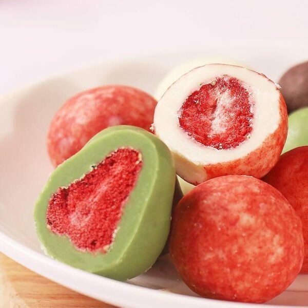White and matcha chocolate balls cut open to show freeze-dried strawberry