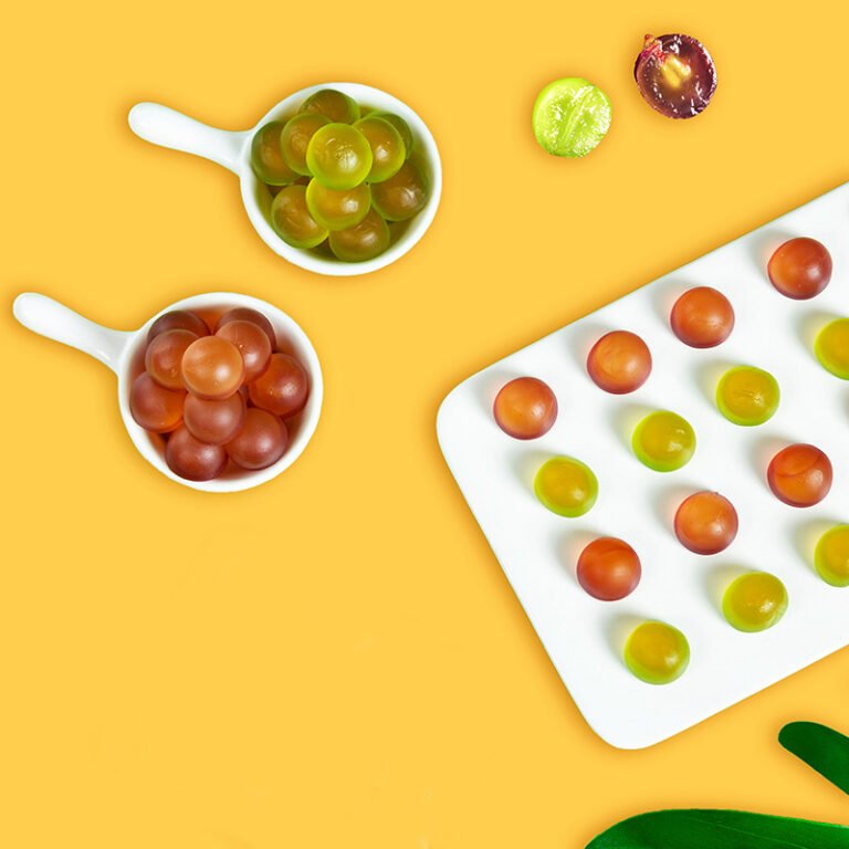Round grape-style gummies in green and red on a tray