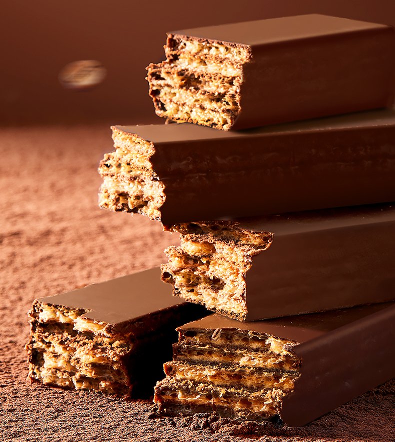 Stacked chocolate-coated crisp bars on cocoa powder