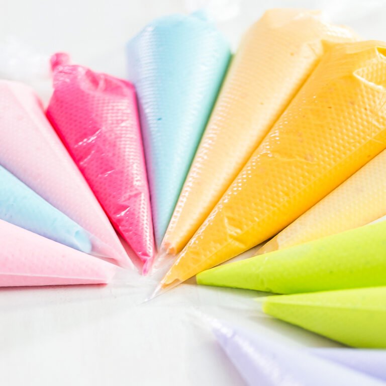 Rainbow of filled disposable piping bags in pink, blue, yellow and green