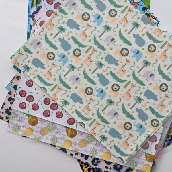 Stack of printed transfer sheets with safari animal and fruit patterns
