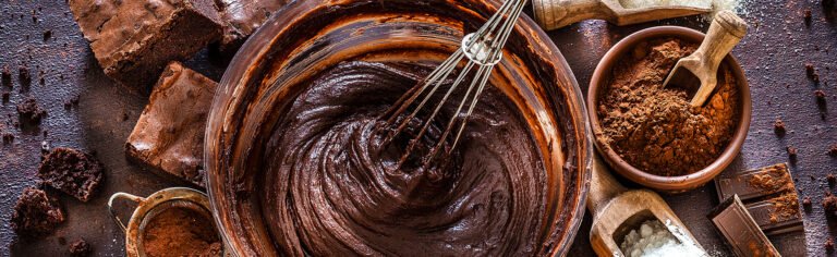 Bowl of chocolate batter with cocoa powder and brownies