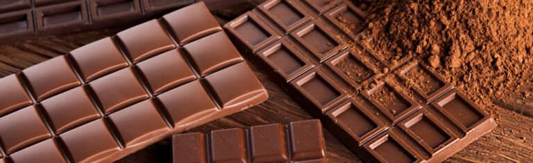 Milk and dark chocolate bars with cocoa powder on a wooden board