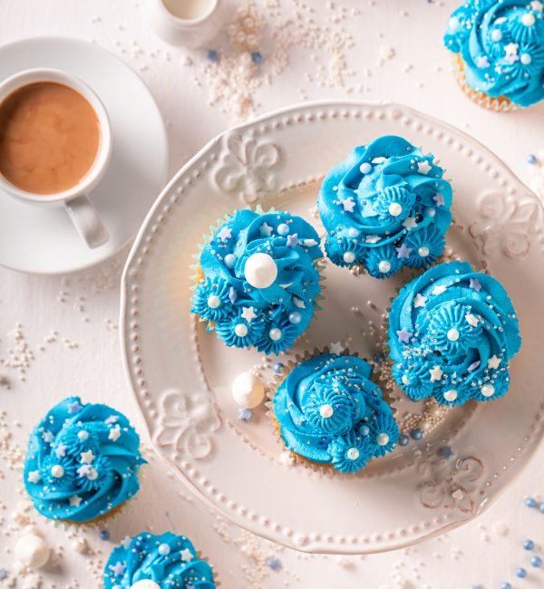 Cute blue cupcakes with flower shaped cream. Blue cupcakes with coffee.